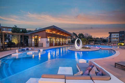 a swimming pool at night with a building in the background